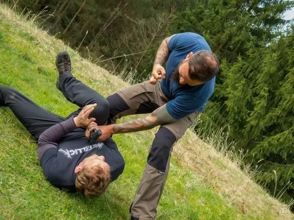 Zwei Personen im Bodenkampf, einer hält den anderen am Arm fest