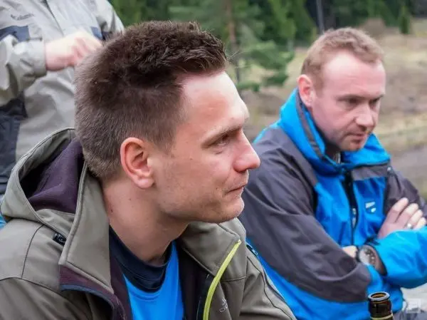 Zwei Personen in Outdoor-Bekleidung sitzen nebeneinander und schauen nachdenklich