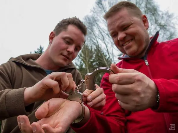 Zwei Personen legen Handschellen an ein Handgelenk an