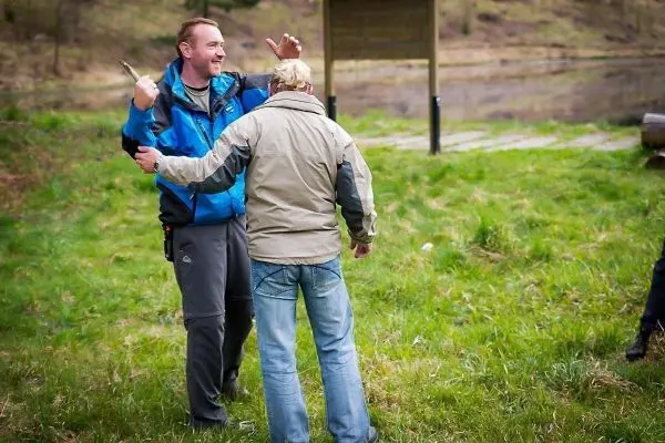 Zwei Personen stehen auf einer Wiese, eine Person hält ein Messer in der Hand