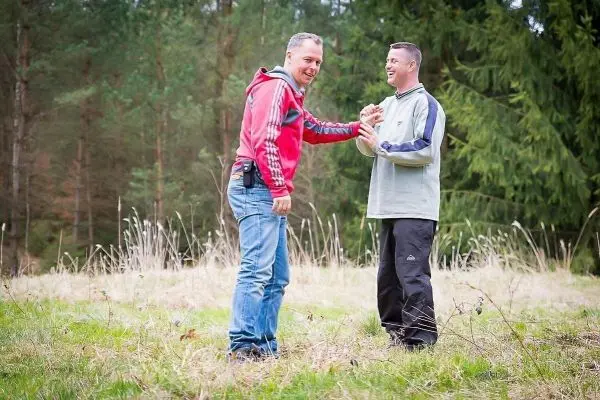 Zwei Personen stehen auf einer Wiese und interagieren freundlich miteinander