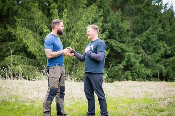 Zwei Personen stehen auf einer Wiese und schütteln sich die Hände