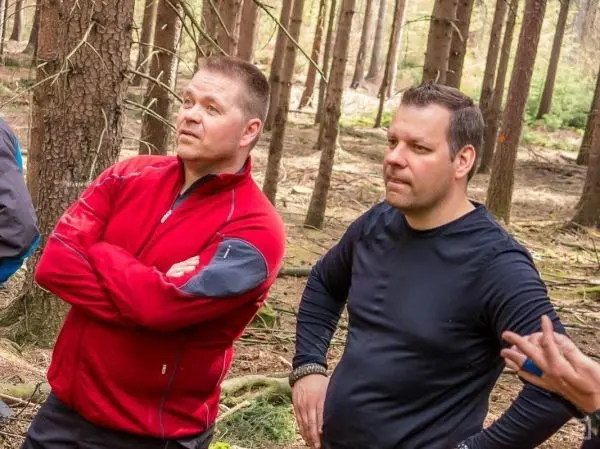 Zwei Personen stehen im Wald und beobachten aufmerksam