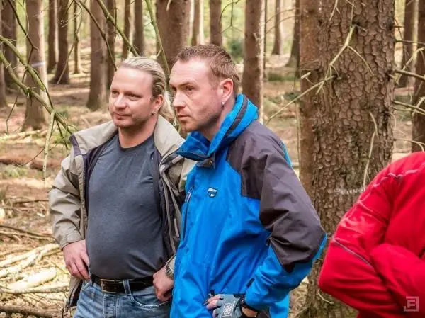 Zwei Personen stehen im Wald und beobachten die Umgebung