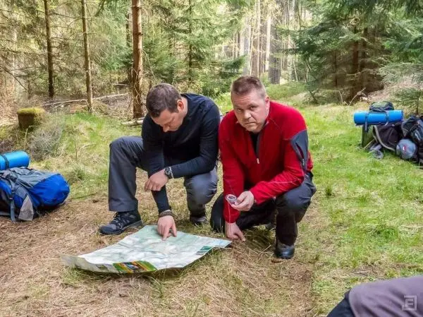 Zwei Personen studieren eine Karte im Wald, eine Kompass in der Hand