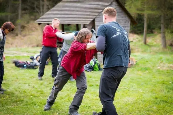 Zwei Personen üben eine Selbstverteidigungstechnik auf einer Wiese