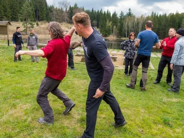 Zwei Personen üben eine Selbstverteidigungstechnik auf einer Wiese