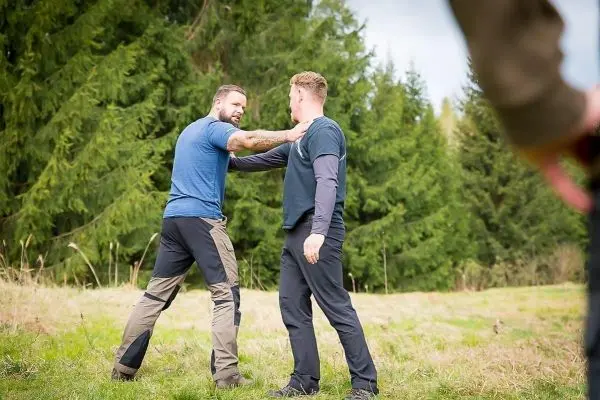 Zwei Personen üben eine Selbstverteidigungstechnik auf einer Wiese