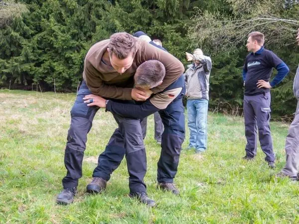 Zwei Personen üben eine Selbstverteidigungstechnik auf einer Wiese