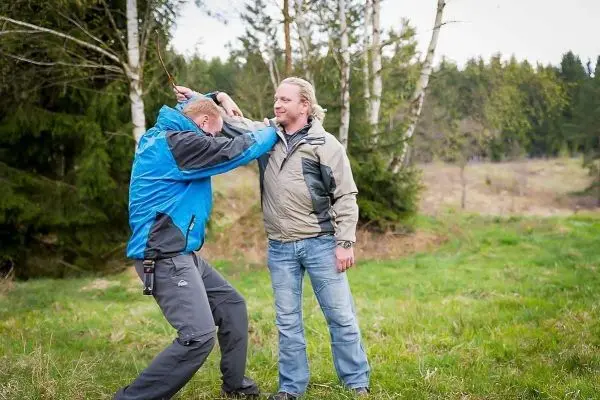 Zwei Personen üben eine Selbstverteidigungstechnik im Freien auf einer Wiese