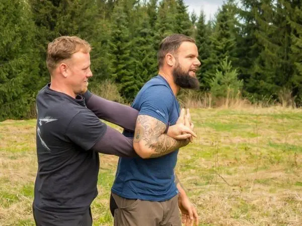 Zwei Personen üben eine Technik zur Kontrolle des Arms im Freien