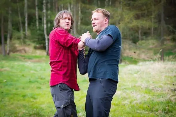 Zwei Personen üben einen körperlichen Griff im Freien aus