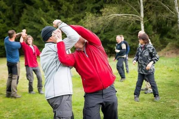 Zwei Personen üben einen Nahkampfgriff auf einer Wiese