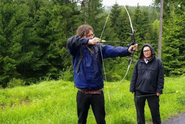 Bogenschütze spannt Pfeil und Bogen in einer Waldlandschaft