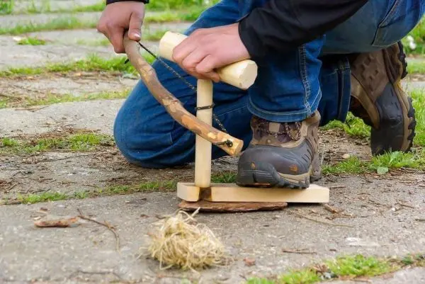 Feuerbohrer erzeugt durch Druck und Drehung Funken auf Zunder