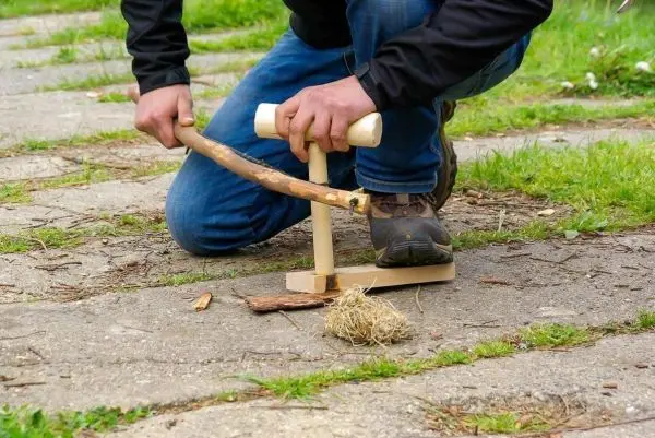 Feuerbohrer wird auf Zunder gedrückt, um Glut zu erzeugen