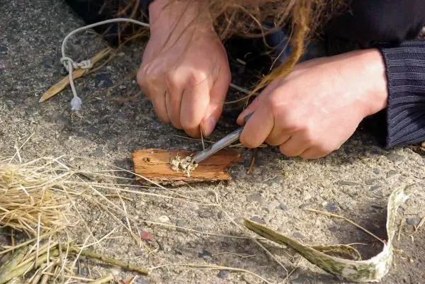 Feuerstahl erzeugt Funken auf Zunder auf Holzstück