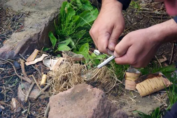 Hände zündeln Zunder mit einem Feuerstahl und Funkenflug