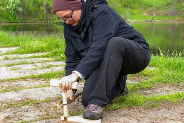 Holzstück mit Kerbe wird zur Feuererzeugung bearbeitet