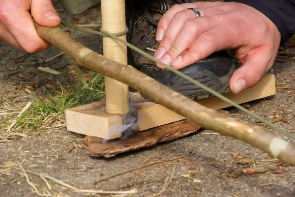 Holzstück reibt an einer anderen Holzoberfläche zur Feuererzeugung