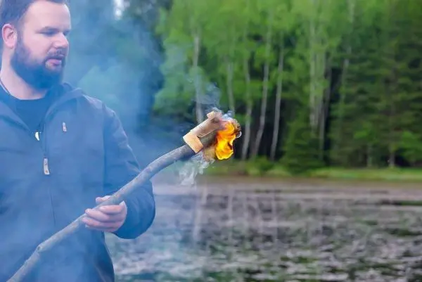 Kleine Flamme brennt an einem Holzstock mit Zunder