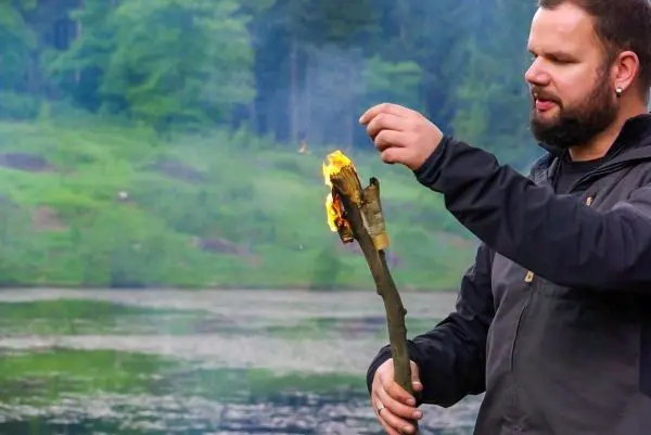 Kleine Flamme brennt an einem Stock, während er gehalten wird