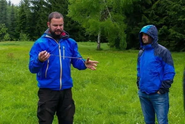 Mann erklärt eine Technik mit einem langen Stock in einer grünen Wiese