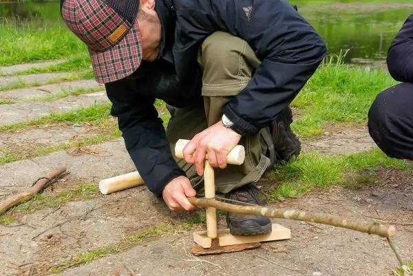 Mann nutzt eine Holzbohrmaschine, um ein Loch in ein Stück Holz zu bohren