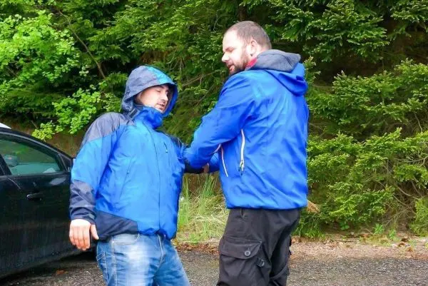 Person hilft anderer Person beim Stehen