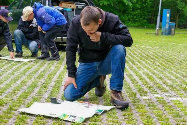Person kniet und betrachtet Unterlagen auf dem Boden beim Überlebenstraining