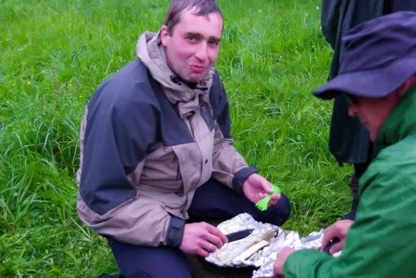 Person sitzt auf dem Boden und isst aus Alufolie