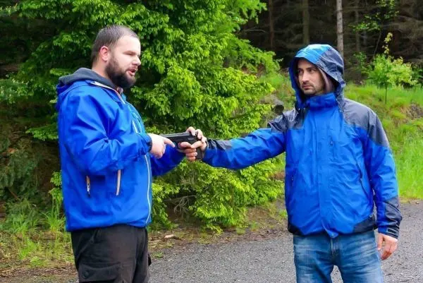Person übergibt ein Objekt an eine andere Person im Freien