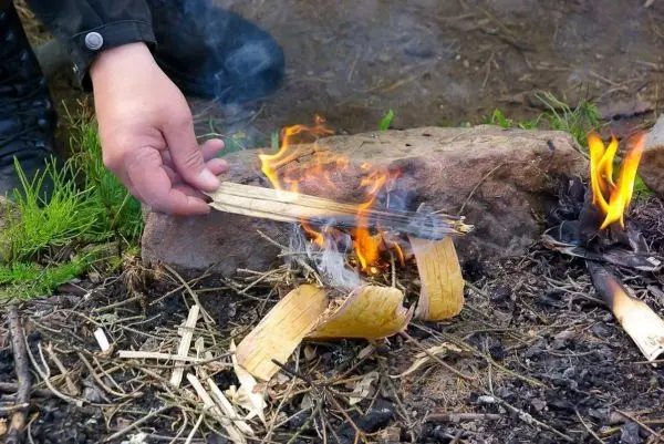 Zunder glimmt und kleine Flamme entsteht auf dem Boden