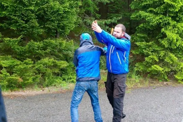 Zwei Personen stehen auf einem Weg, eine Person zeigt mit der Hand in eine Richtung