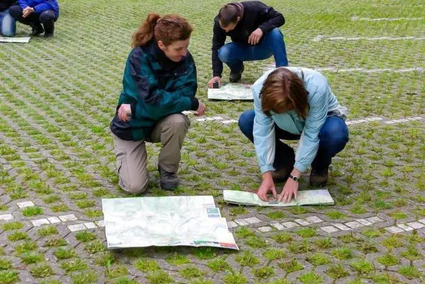 Zwei Personen studieren Karten auf dem Boden beim Überlebenstraining