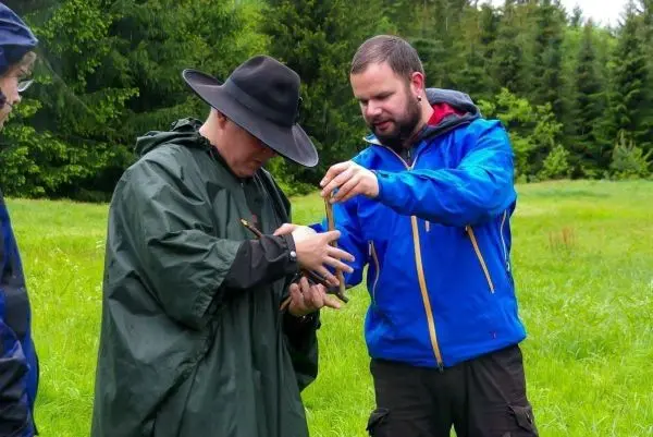 Zwei Personen zeigen gemeinsam auf ein Objekt in der Hand des Mannes mit Hut