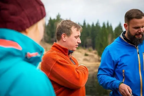 Drei Personen stehen am Ufer eines Gewässers und unterhalten sich