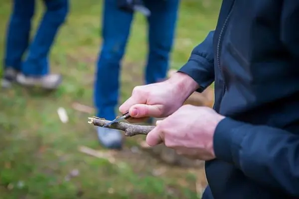Ein Messer schneidet einen Stock in der Hand
