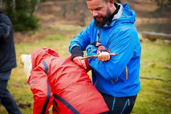 Eine Person demonstriert eine Technik zur Unterstützung einer anderen Person mit einem Stock