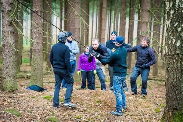 Gruppe arbeitet an einer selbstgebauten Seilquerung zwischen Bäumen im Wald