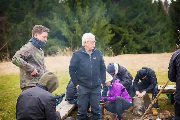 Gruppe arbeitet an Holzarbeiten und Feuerstelle im Freien