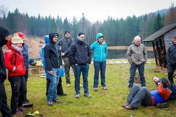 Gruppe beobachtet eine praktische Übung am Ufer eines Gewässers