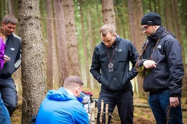 Gruppe betrachtet selbstgebaute Konstruktion im Wald, umgeben von Bäumen