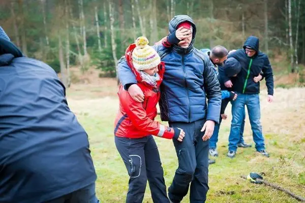 Gruppentraining zur Erste-Hilfe mit einer Person, die unterstützt wird und Augenbinde trägt
