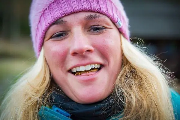 Lächelnde Person mit blonder, langer Haarpracht und rosa Mütze