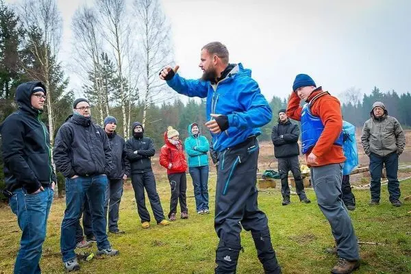 Mann in blauer Jacke demonstriert eine Technik vor einer Gruppe von Zuschauern