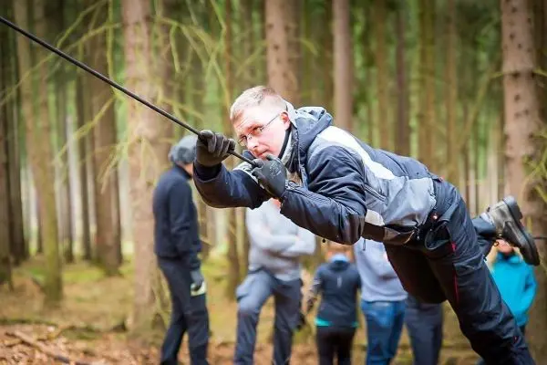 Mann überquert eine selbstgebaute Seilbrücke zwischen Bäumen