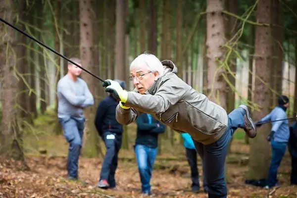 Mann überquert selbstgebaute Seilbrücke im Wald