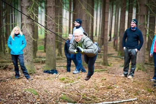 Mann überquert selbstgebaute Seilbrücke zwischen Bäumen im Wald