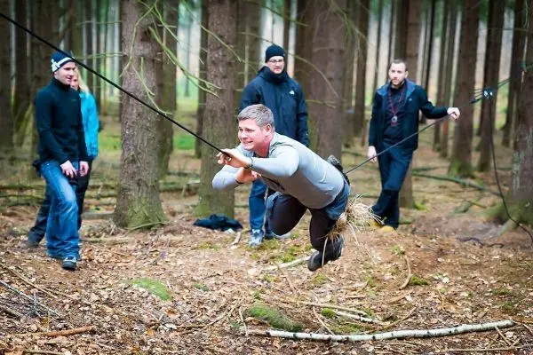 Mann überquert selbstgebaute Seilbrücke zwischen Bäumen im Wald